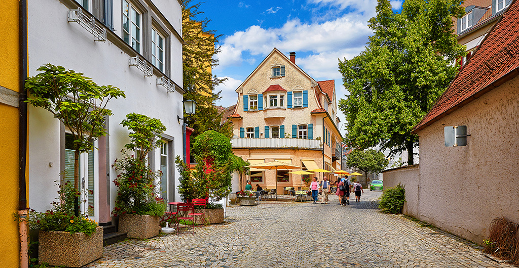 Cosy street in picturesque bavarian town Lindau at Lake Constance (Bodensee) in Germany. Traditional old german houses with cafe. Sunny summer day.