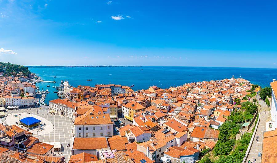 Aerial panorama view of Piran city, Slovenia. Look from tower in church. In foreground are small houses, Adriatic sea in background. Summer weather in famous tourist destination.