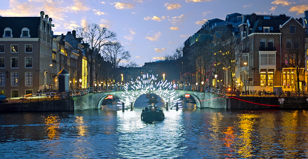 Amsterdam lights in the city center at the river Amstel in the Netherlands at sunset