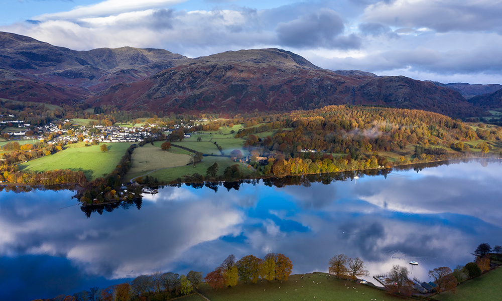 Stunning aerial drone landscape images over Coniston Water at sunrise on beautiful Autumn Fall morning