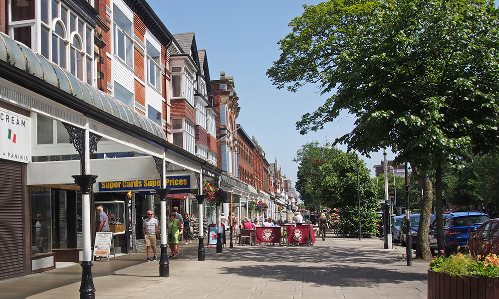 southport, merseyside, united kingdom - 28 june 2019: people sitting at outdoor cafes and walking past shops in the historic lord street shopping area in southport merseyside