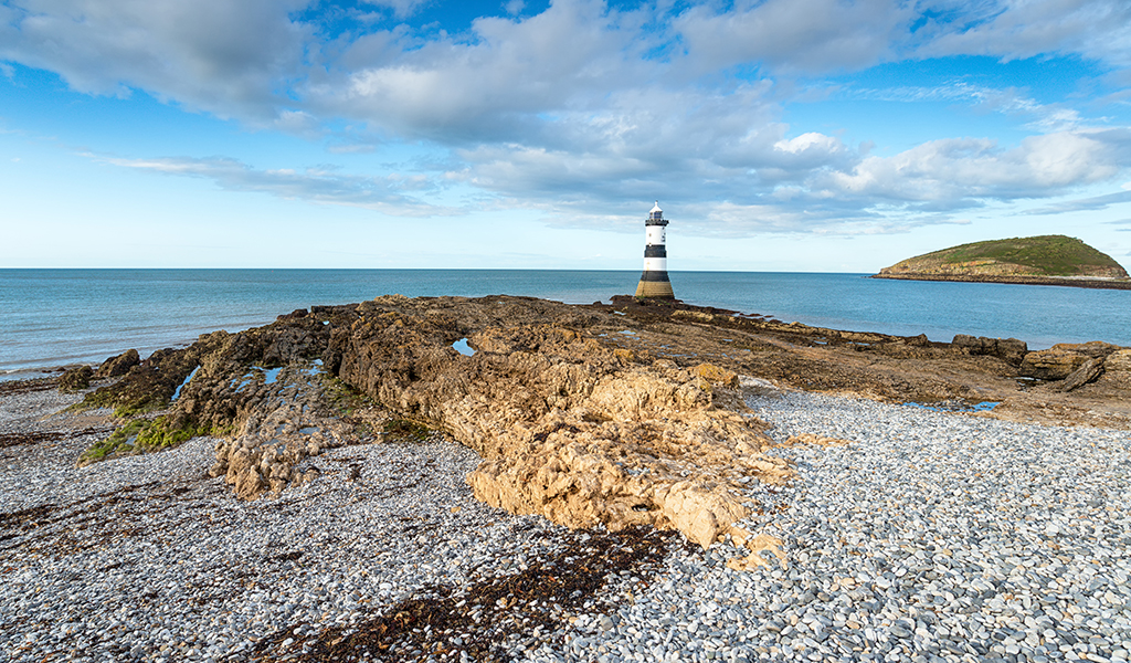 Trwyn Du lighthouse at Penmon Point on the coast of Anglesey with Puffin Island in the distance